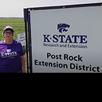 Sandra Wick standing by wheat test plot sign